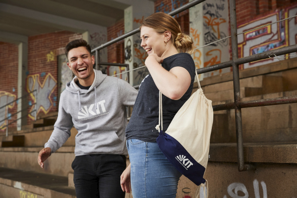 Ein Student und eine Studentin lachen und tragen Kleidung mit KIT-Logo