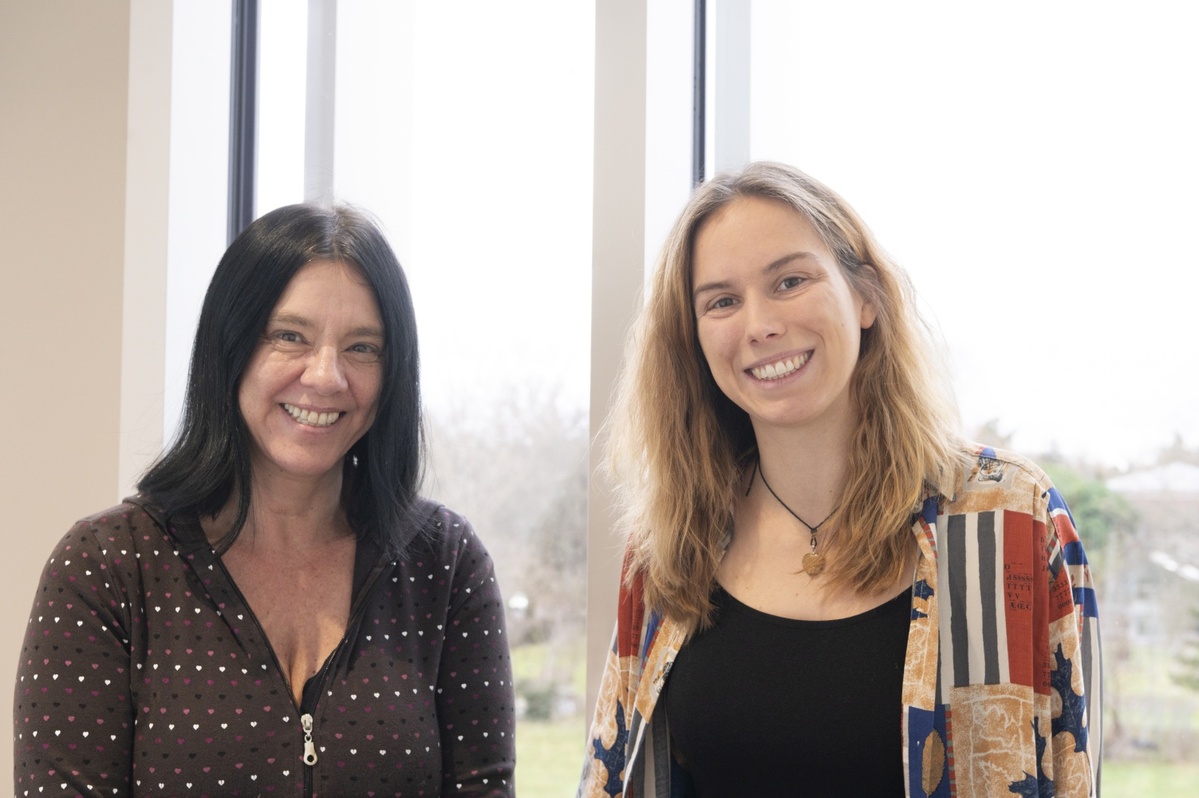 Gabi Zachmann und Julia Thomas stehen lächelnd nebeneinander vor einem Fenster.